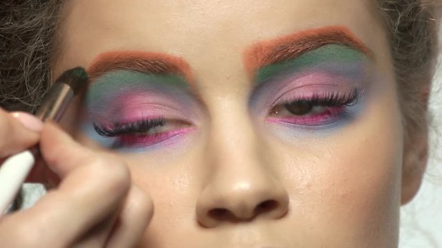 Hand with eyeshadow brush. Colorful eye makeup.