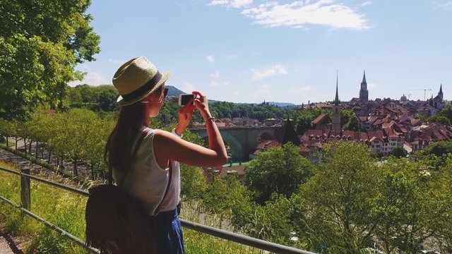 Tourist Woman Taking Photographs in Bern, Switzerland. 4K. Traveller Making Pictures with a Smartphone of The Old Town of Bern from a view point near Rosengarten in summer. Travel Europe concept.