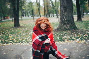 Fototapeta na wymiar redhead girl on red plaid in autumn park
