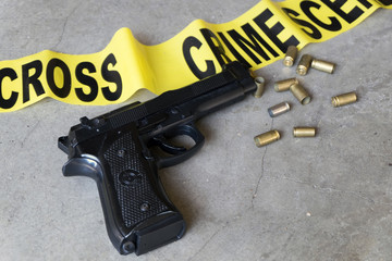 Crime scene concept with black gun and crime scene tape from above