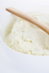 A bowl of milk powder and spoon. Close up.