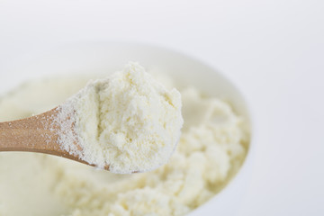A bowl of milk powder and spoon. Close up.
