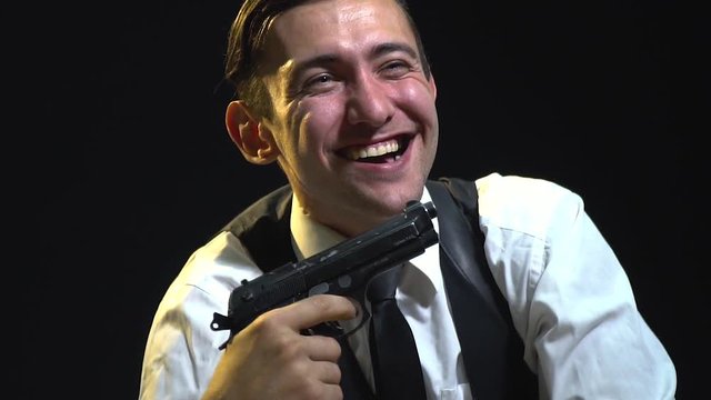 A man with a gun is having fun and making faces in a dark room