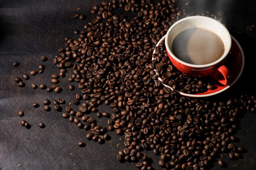 Hot coffee in red cup and coffee beans are the background.