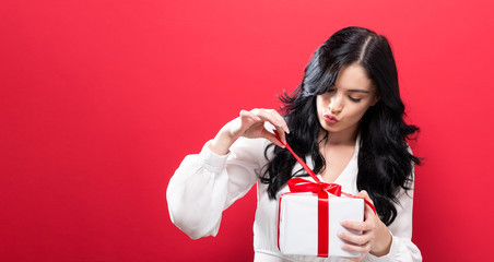  Happy young woman holding a gift box on a solid background