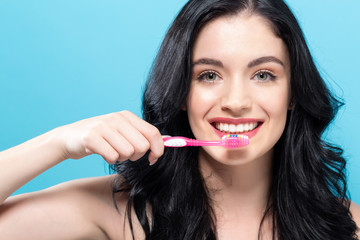 Young woman holding a toothbrush on a solid background
