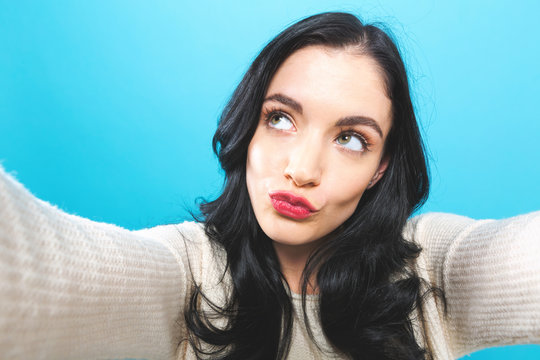 Young woman taking a selfie on a blue background