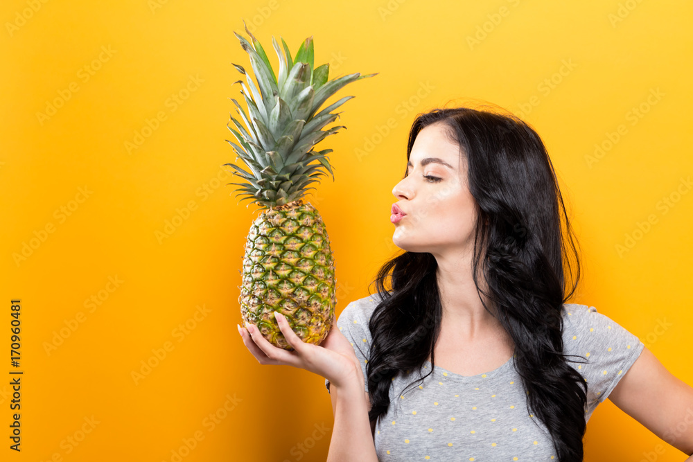 Canvas Prints happy young woman holding a pineapple on a yellow background