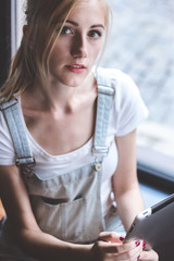 Having opportunity to work anywhere.Top view of cheerful young woman holding digital tablet while sitting at the wooden counter in cafe.