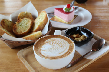 Hot cappuccino, biscuit, cake and bread in morning time.
