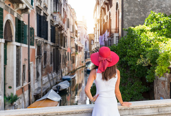 Weibliche Touristin mit rotem Hut schaut auf einen Kanal in Venedig, Italien