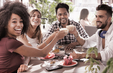 group of young friends at coffee shop drinking cappuccino laughing together