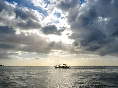 Fishing boat in the Caribbean sea at sunset with low clouds in the sky over the sea.