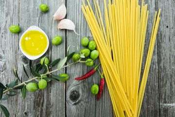 Ingredients for cooking Italian pasta - spaghetti oil, garlic and chili on a rustic wooden background