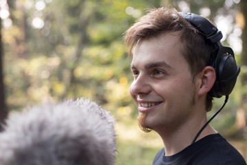 Tontechniker mit Kopfhörer und Mikrofon, draußen