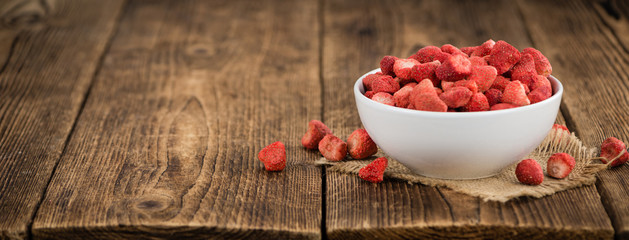 Strawberries (dried) on wooden background; selective focus