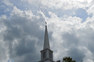 photo of a church steeple with the sun shining through the clouds