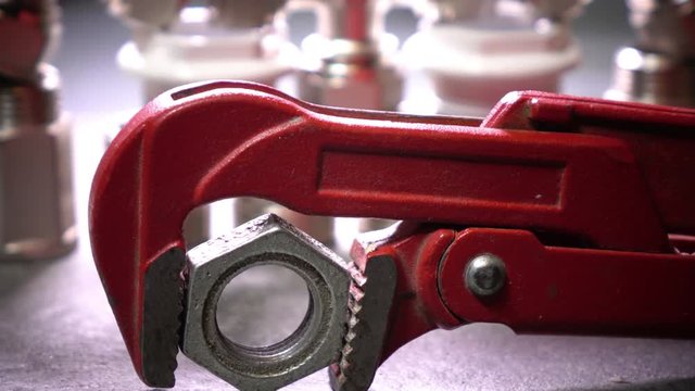Red metalwork adjustable spanner for sanitary works against the background of Water shutoff and connecting shutoff valves for water supply