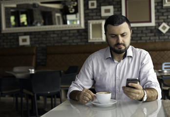 Fototapeta na wymiar Handsome man texting on the phone in cafe