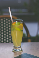 Lemonade glass with mint leaves, lime slices and colorful straw