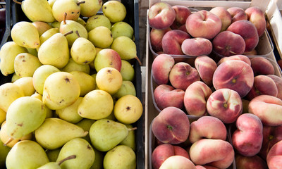 Heap of pear and peach fruits on market stall