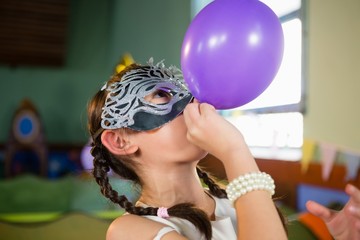 Adorable girl blowing balloon during birthday party