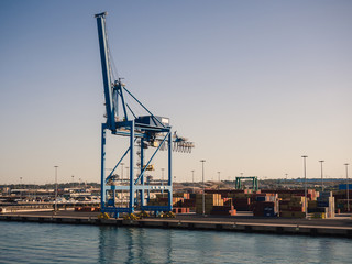 Fototapeta premium Shipping industrial trade port. Crane bridge and import export container at shipping port harbor.