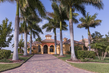 Fototapeta na wymiar Typical Southwest Florida concrete block and stucco home in the countryside with palm trees, tropical plants and flowers, grass lawn and pine trees. Florida