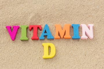 Word vitamin D of colored wooden letters on sandy beach