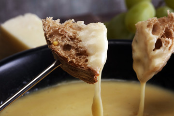 Gourmet Swiss fondue dinner on a winter evening with assorted cheeses on a board alongside a heated...