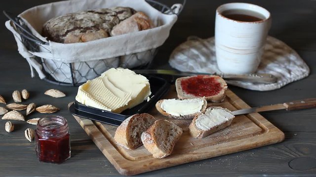 A Woman Smeared Black Bread With Raspberry Jam And Butter. A Small Jar Of Jam Is On The Thiol.