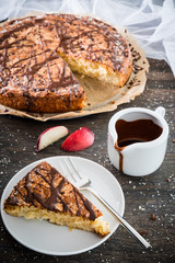 Ein Stück Nektarinenkuchen mit ganzem Kuchen im Hintergrund