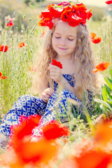 Obraz na płótnie Canvas Little cute little girl in a wreath of poppies