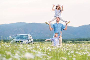 Father and children on offroad car playing in the field