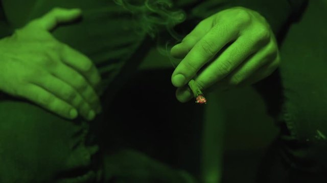 process of smoking a close-up Joint
 with marijuana in the green light of a coffeeshop. the legalization of marijuana in the world, the culture of smoking weed. 