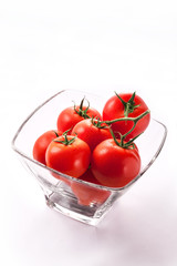 Tomatoes branch with water drops closeup in glass jar isolated on white background in studio