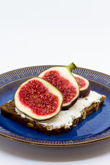 Figs and cheese on a bread. Sandwich on a plate, white background.
