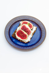 Figs and cheese on a bread. Sandwich on a plate, white background.