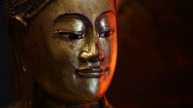 Ancient gold buddhist scuplture with orange light on dark background - focus