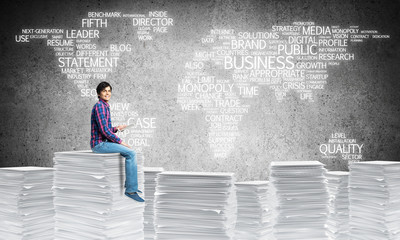 Attractive man sitting on pile of paper documents.