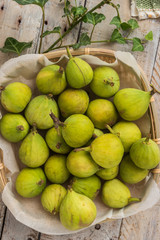 Whole figs in wicker basket on top of a rustic wooden table.