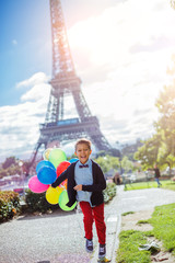 Boy with bunch of colorful balloons in Paris near the Eiffel tower.