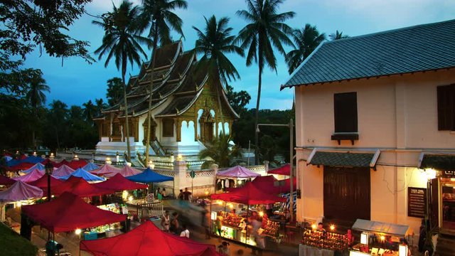 Luang Prabang, Laos. Famous night market in Luang Prabang, Laos with illuminated temple and sunset sky. Time-lapse at sunset