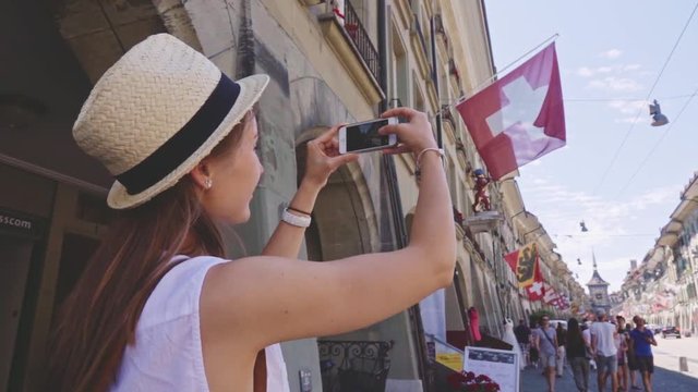 Tourist Woman Taking Photographs in Bern, Switzerland. SLOW MOTION 240 fps. Traveller making a Picture of Kramgasse with a Smartphone in the Old Town of Bern in summer. Travel Europe concept 