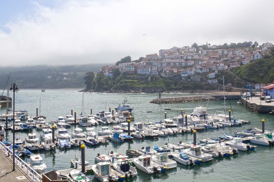 boats in a port in Lastres with the village behind, Asturias, Spain