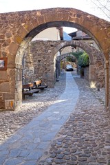 street full of stone archs with a car in Potes, Spain