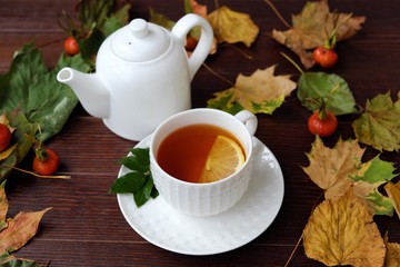 Tea with lemon on the table with autumn leaves 