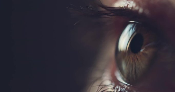Macro Close-up Eye Blinking. SLOW MOTION 4K DCi. Young Woman is opening and closing her hazel eye. Eyesight health. Cinematic close up shot on dark background.
