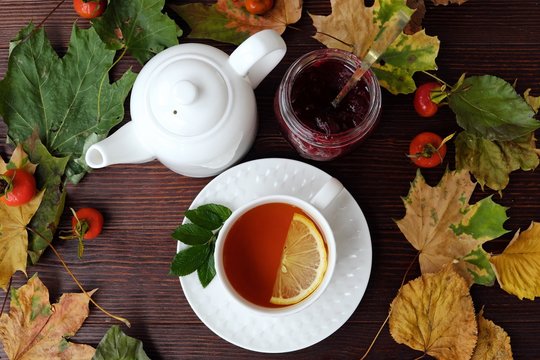 Tea with lemon and jam on table with autumn leaves