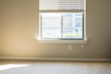 Corner view of clean apartment bedroom with window view, natural light and vacuuming rough carpet. Typical apartment bedroom detail in America.